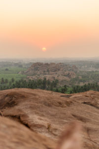Large rock in palm landscape with setting sun in the background. Large rock in palm landscape with setting sun in the background.